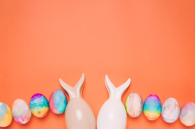 Two easter eggs with bunnies ear on orange background