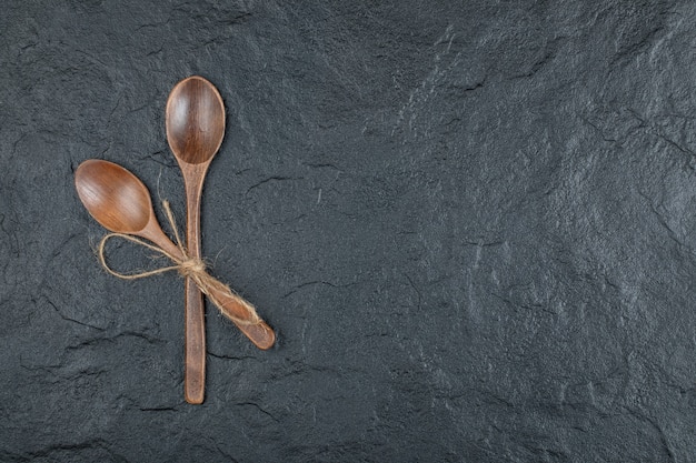 Free photo two empty wooden spoons on a dark background.