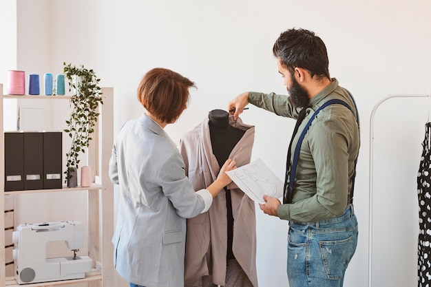 Two fashion designers in atelier with dress form