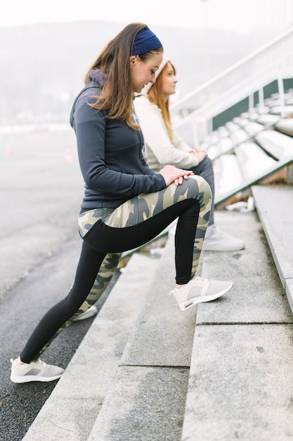 Free photo two female athlete stretching her leg on steps