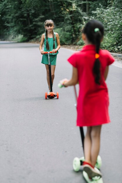 Two female friend standing on scooter looking at each other