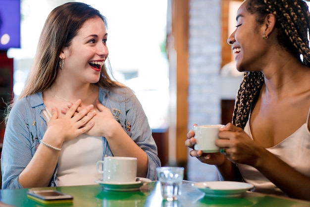 Free photo two female friends enjoying a cup of coffee together.