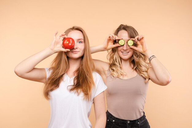 Two female friends keeping healthy tomatoes and cucumbers