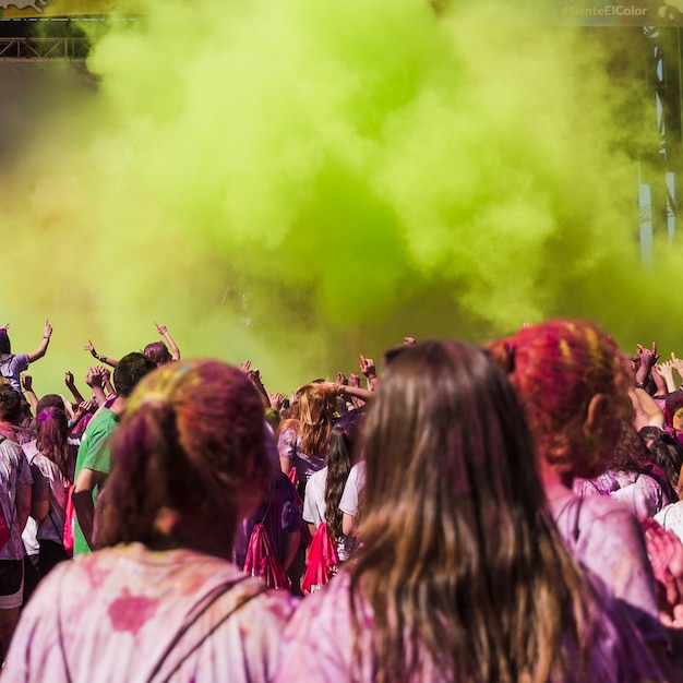 Free photo two female friends looking at people dancing in the holi color explosion