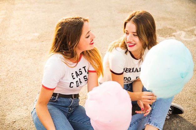 Free Photo two female friends with candy floss looking at each other