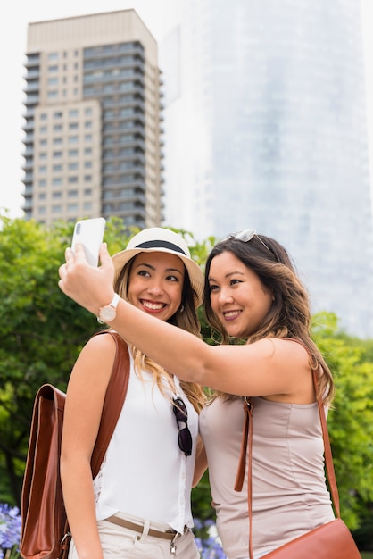 Two female tourist with their backpack taking selfie on cellphone at outdoors