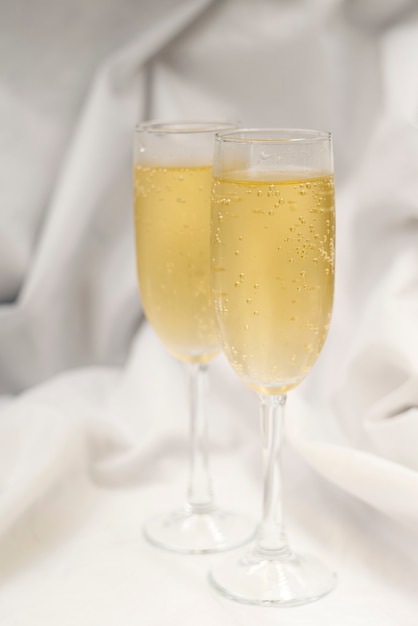 Two filled champagne flute over white textile