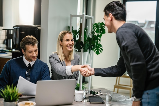 Free photo two financial advisors having a meeting with young man at home female advisor is shaking hands with a client