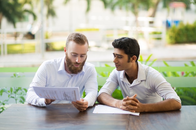 Free Photo two focused business men meeting and working in outdoor cafe