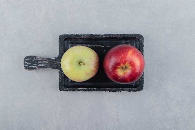 Two fresh apples on black cutting board. 