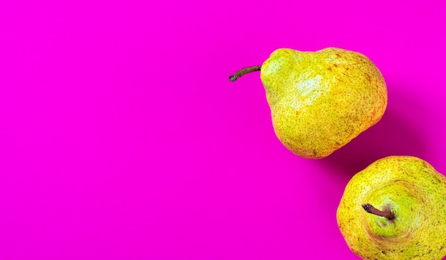 Free photo two fresh pears on pink paper surface