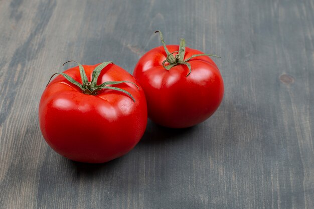 Two fresh raw tomatoes with leaves on a wooden table