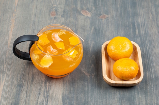 Free Photo two fresh tangerines with a glass jar of juice 