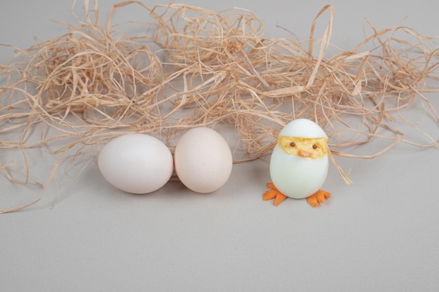 Free photo two fresh white chicken eggs with chicken toy and hay .