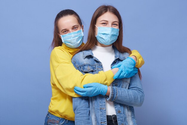 Two friends being in good mood, wearing medical masks and gloves