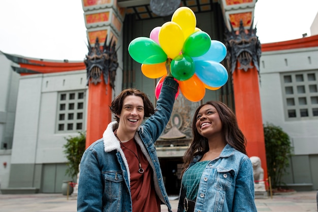 Free photo two friends having fun with balloons while out in the city