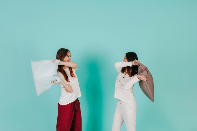 Free photo two friends having pillow battle