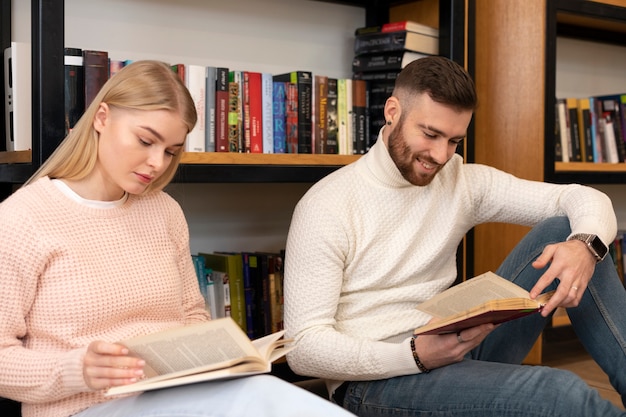 Two friends reading books in a library