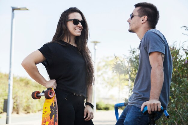 Two friends with longboard and bicycle