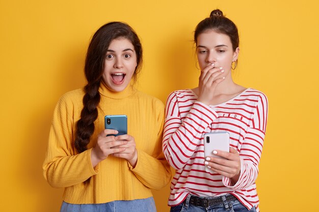 Two friends with phones reading shocking news in social network