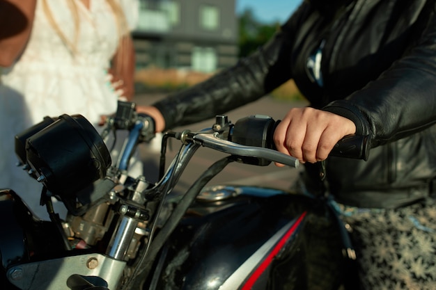 Two girl friends stay near motorbike. Sell motorcycle concept in the city.