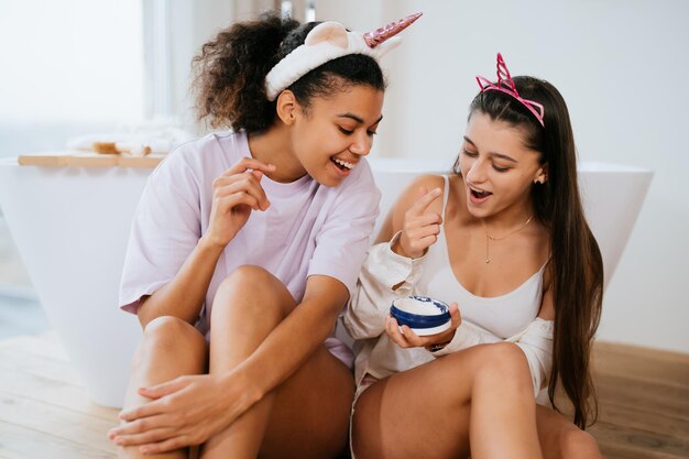 Two girls in the bath playing with face cream