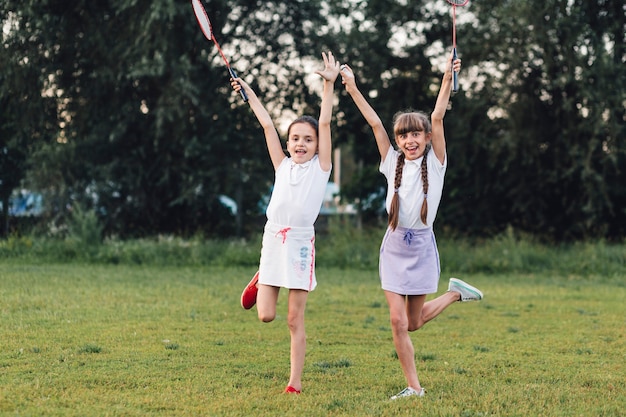 Two girls enjoying in the park holding badminton