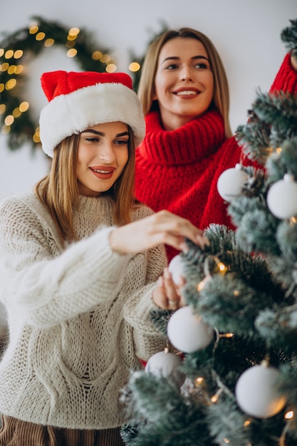 Free photo two girls friends by the christmas tree