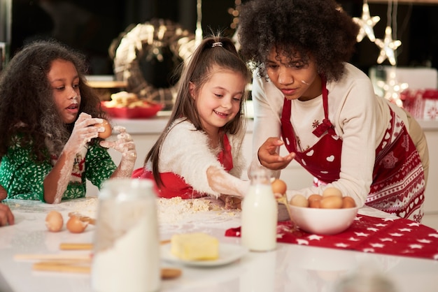 Two girls making cookies with mom at Christmas