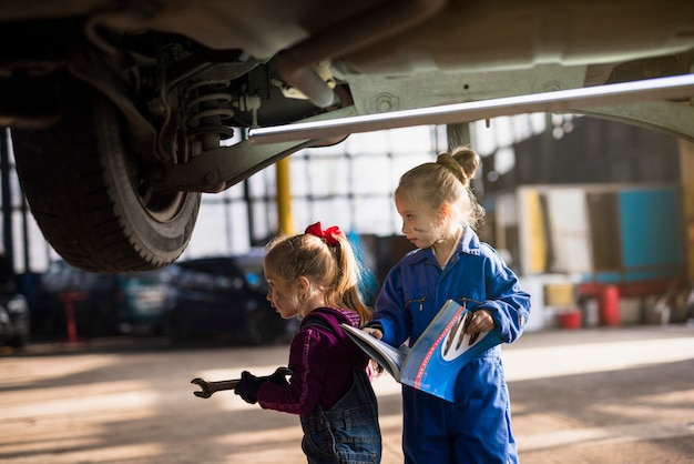 Two girls in overalls standing with spanner and magazine