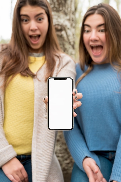 Free photo two girls presenting smartphone mockup