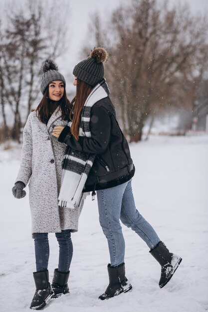 Two girls walking together in a winter park