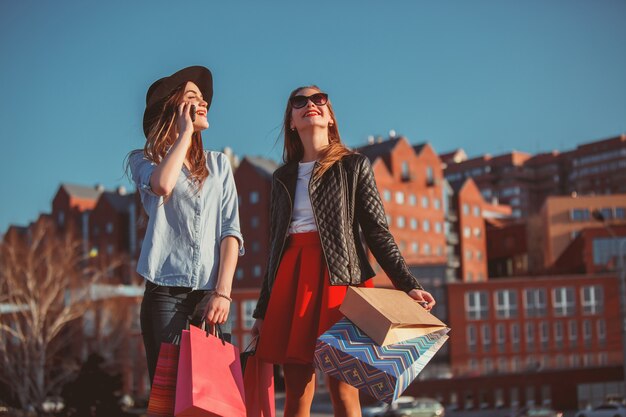 Two girls walking with shopping on city streets