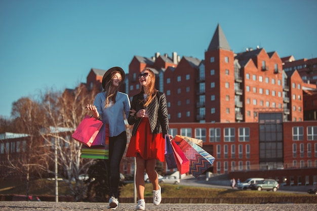 Two girls walking with shopping on city streets