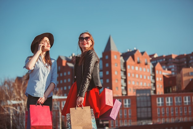 Free photo two girls walking with shopping on city streets