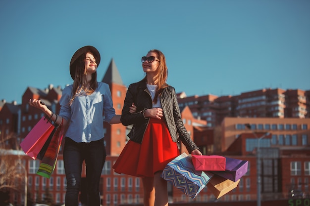 Free photo two girls walking with shopping on city streets