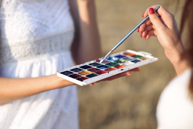 Free photo two girls in a white dress painting in a field