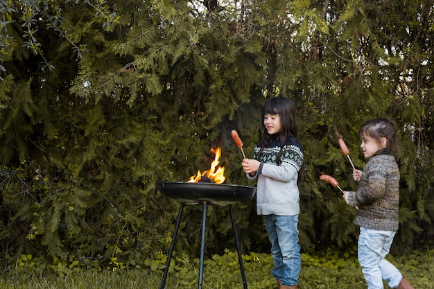 Two girls with sausages standing near barbecue