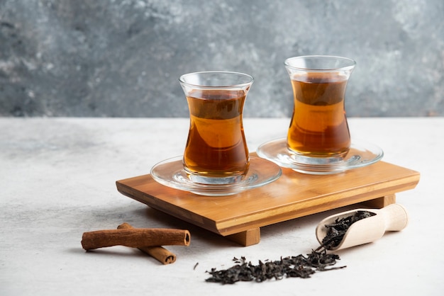 Two glass cups of tea with cinnamon sticks and loose teas.High quality photo