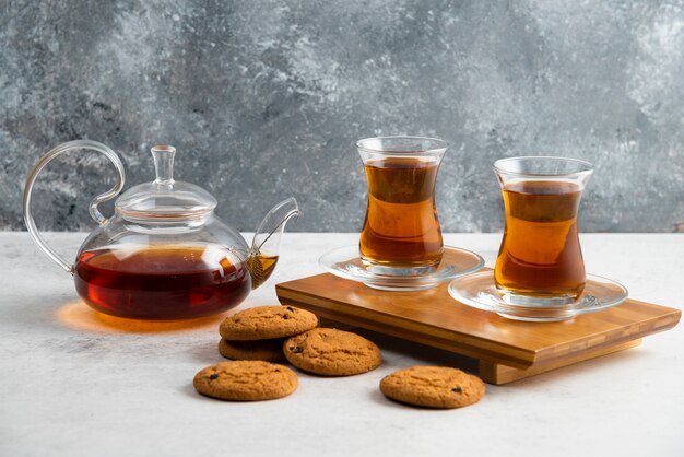 Two glass cups of tea with delicious cookies .