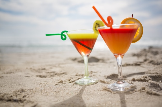 Two glasses of cocktail drink kept on sand