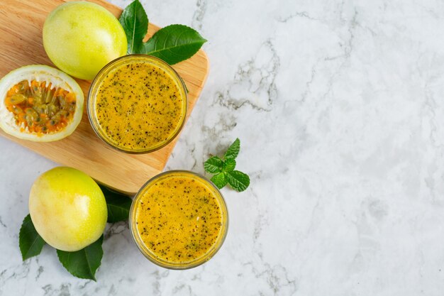 two glasses of passion fruit juice place on white marble floor