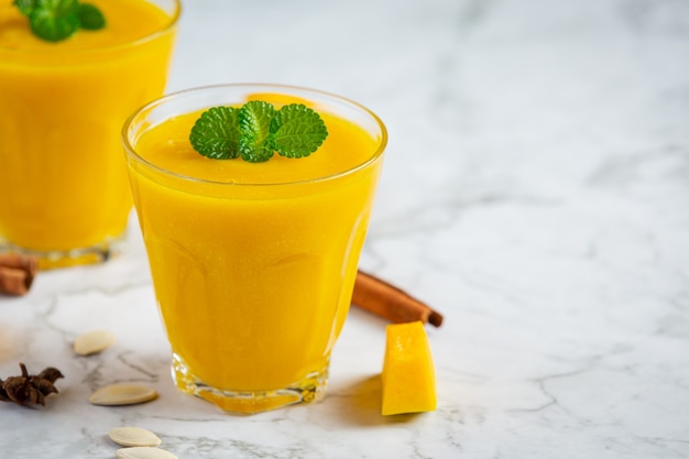 two glasses of pumpkin juice place on white marble  floor