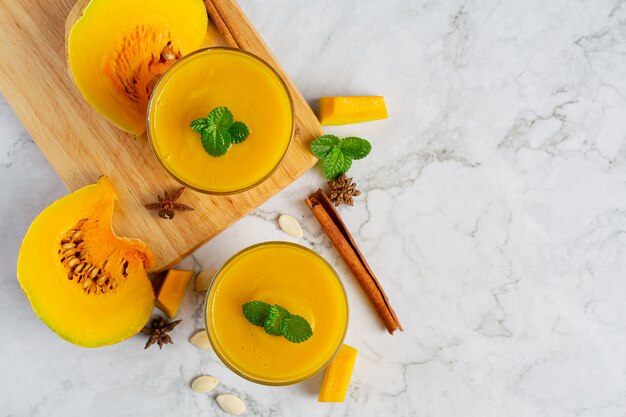 two glasses of pumpkin juice place on white marble  floor