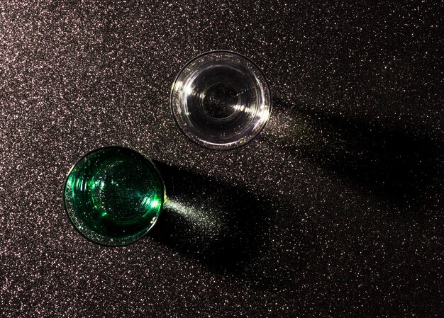 Two glasses of water on shiny black background