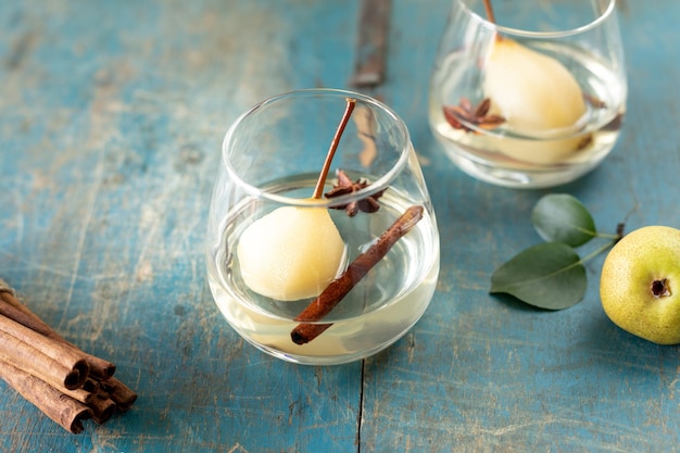 Two glasses with a drink with sweet pears stewed in white wine on a wooden table Festive dessert