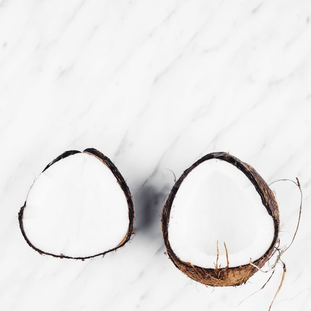 Free Photo two halves of ripe coconut on white marble background