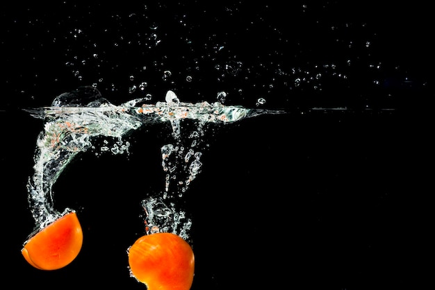 Free Photo two halves tomatoes falling into clean water with splash