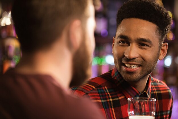 Two happy male friends drinking beer at bar