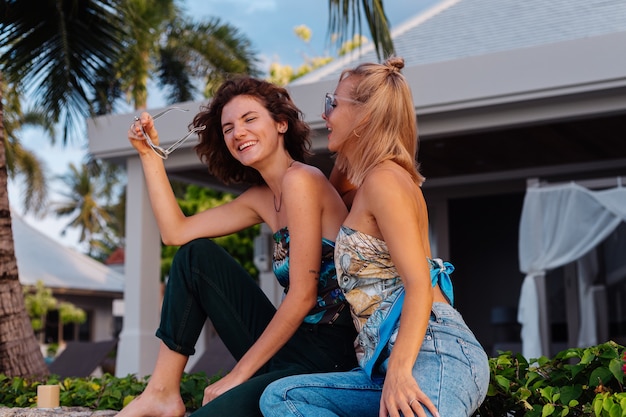 Two happy woman friends with sunglasses on vacation in tropical country